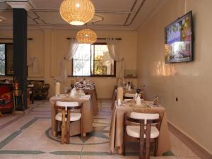 a dining room with tables and chairs and chandeliers at Riad Perlamazigh in Zagora