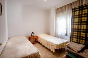 a small room with two beds and a window at MAQUINILLA PORTAL 4A in Nerja