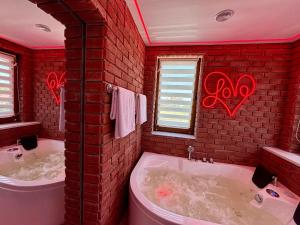 a red brick bathroom with two tubs and a window at Apartament "Loft Love" Jacuzzi SPA z dużą wanną z hydromasażem dla Dwojga in Gniezno