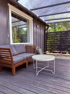 a patio with a couch and a table on a deck at Pussala Latgalē in Ezerukiņi