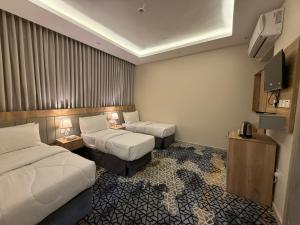 a hotel room with two beds and a television at فندق ندى أجياد in Ajyad