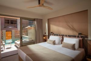 a bedroom with a large bed and a large window at Esperides Resort Crete, The Authentic Experience in Hersonissos +117 photos