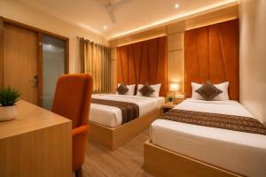 a hotel room with two beds and a desk at Hotel Nayyar Regency Near Golden temple in Amritsar