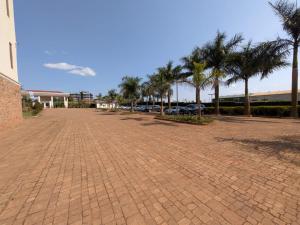 a brick parking lot with palm trees and a building at Kampala Nile Resort in Seeta