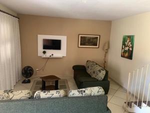 a living room with a couch and a tv at Pousada Recanto Penedo in Penedo +6 photos