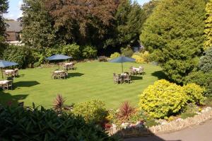 a garden with tables and chairs and umbrellas at Stow Lodge Hotel in Stow on the Wold