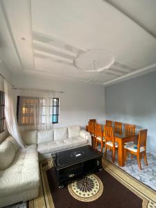 a living room with a white couch and a table and chairs at Le cozy in Abomey-Calavi