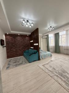 a bedroom with a blue couch and a brick wall at Asia Street in Bishkek