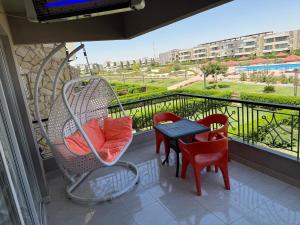 a balcony with a swing and a table and chairs at Blumar El Sokhna in Ain Sokhna