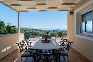 a patio with a table and chairs on a balcony at Sunset Villa Amelia Skiathos in Skiathos National Airport