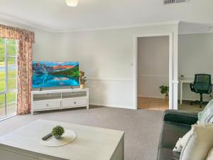 a living room with a couch and a flat screen tv at Suburban Bliss - Elegant Villa 2 in Wagga Wagga