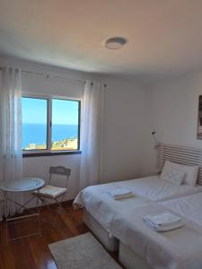 a bedroom with a bed and a table and a window at LandS in Caniço