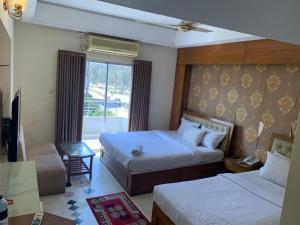 a hotel room with two beds and a window at Hotel Ovisar in Cox's Bazar