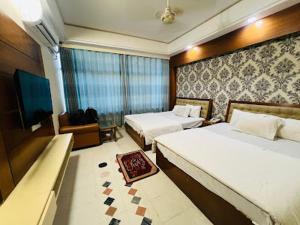 a hotel room with two beds and a television at Hotel Ovisar in Cox's Bazar