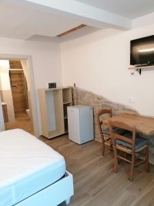 a room with a bed and a table and a refrigerator at Il Grottino in Frontino
