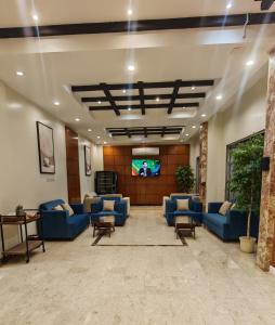 a lobby with blue couches and a flat screen tv at المها إن للشقق المخدومة in Hail