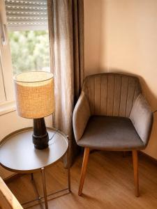 a chair sitting next to a table with a lamp at Lugas Apartman in Harkány +4 photos