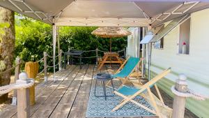 a porch with rocking chairs and an umbrella at Chez Les Garçons Mobile home vintage, confortable avec piscine in Sarlat-la-Canéda