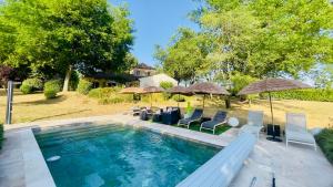 a swimming pool with chairs and umbrellas at Chez Les Garçons Mobile home vintage, confortable avec piscine in Sarlat-la-Canéda