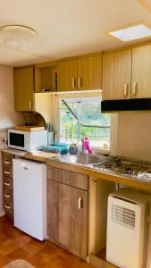 a kitchen with a sink and a stove top oven at Chez Les Garçons Mobile home vintage, confortable avec piscine in Sarlat-la-Canéda