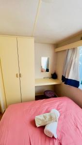 a bedroom with a pink bed with two towels on it at Chez Les Garçons Mobile home vintage, confortable avec piscine in Sarlat-la-Canéda +12 photos