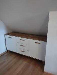 a closet with white cabinets and a wooden floor at Domki pod brzózkami in Bodzentyn +1 photo