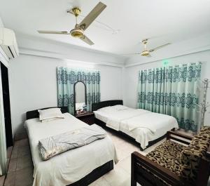a bedroom with two beds and a mirror at Rifaee Cox Palace in Cox's Bazar