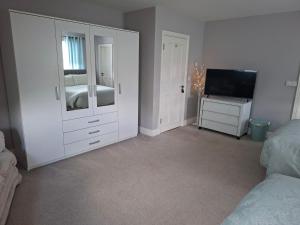 a white bedroom with a bed and a television at White Quarry Hse Quarry Road in Navan