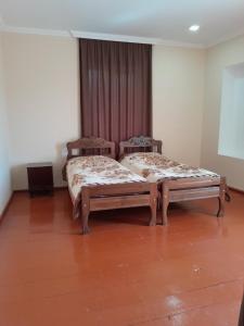 two beds in a room with wooden floors at Guest house Tea in Kvareli