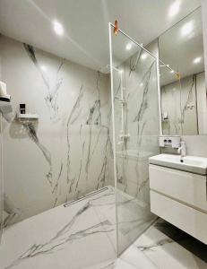 a white bathroom with a shower and a sink at Білі апартаменти in Dnipro