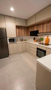 a large kitchen with white appliances and wooden cabinets at 3BDS Luxury Stay Apartment - شقة 3 غرف للإقامة الفاخرة in Jeddah