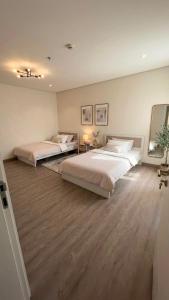 two beds in a large bedroom with wood floors at 3BDS Luxury Stay Apartment - شقة 3 غرف للإقامة الفاخرة in Jeddah