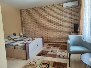 a bedroom with a brick wall and a bed and a chair at Jasen restoran in Jarmenovci