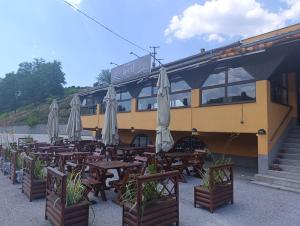 a restaurant with tables and umbrellas in front of a bus at Jasen restoran in Jarmenovci