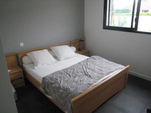 a small bedroom with a bed with white sheets and a window at Villa proche de Bordeaux in Gradignan