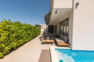 a patio with a couch and a table next to a pool at Villa Nika with pool & parking near Zadar in Bibinje