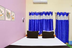 a room with a bed with blue curtains at Super Hotel O A.R. Lodge in Durgāpur +37 photos