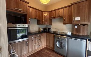 a kitchen with wooden cabinets and a washer and dryer at Flat 4, 2 Victoria Street in Armagh