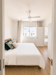 a white bedroom with a white bed and a window at Blue Zebra - Le West 24 in Tamarin