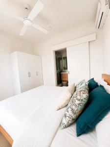 a bedroom with a white bed with pillows on it at Blue Zebra - Le West 24 in Tamarin