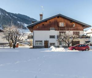 una casa con un coche rojo aparcado en la nieve en Apartments da Edvige, en Tarvisio