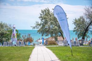 a sign in the grass next to chairs and the ocean at Safir Blue Resort in Saturn