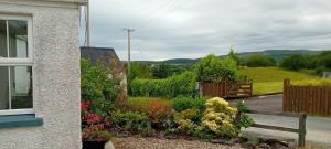 a garden with flowers and a bench next to a house at Rose Cottage in Kilrean