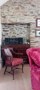 a living room with a piano and a chair at Rose Cottage in Kilrean