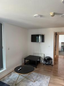 a living room with a table and a tv on the wall at Elysium pro in Bradford