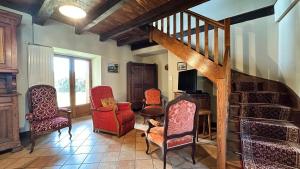 a living room with chairs and a wooden staircase at Le Gite de la Ferme d Issac in Le Nayrac