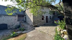 a stone house with a stone walkway in front of it at Le Gite de la Ferme d Issac in Le Nayrac