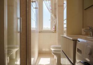 a bathroom with a toilet and a sink and a window at Casa Thaila - Box auto gratuito in Milan