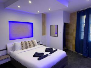 a bedroom with a large white bed with black towels on it at Cardinal Rooftop Townhouse by Aureum in Birgu