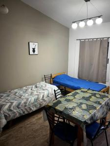 a room with two beds and a table in it at El rincon del viajero deptos in San Francisco del Monte de Oro